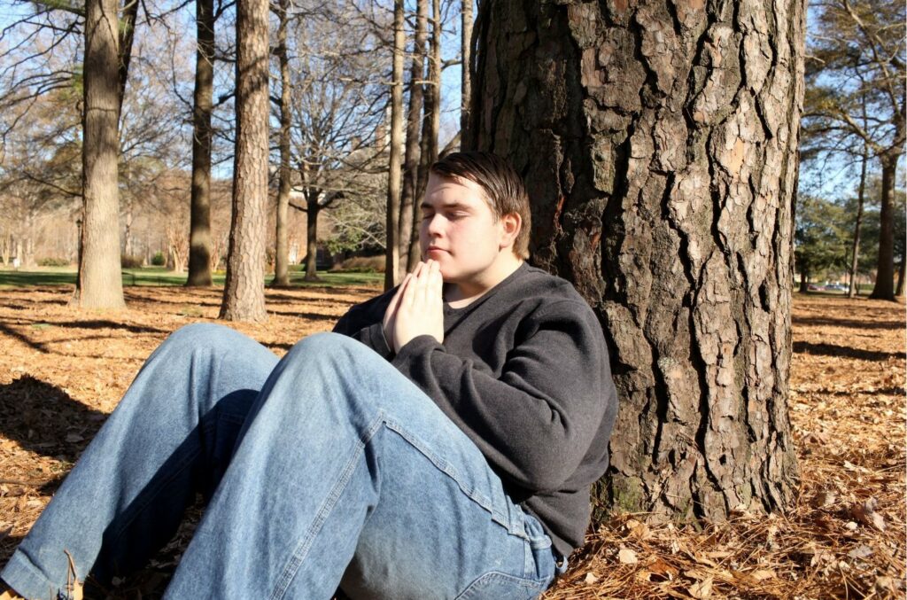 Jeune autiste méditant assis contre un arbre
