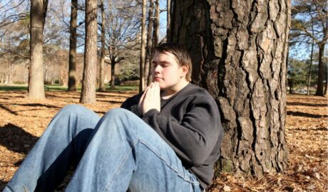 Jeune autiste méditant assis contre un arbre