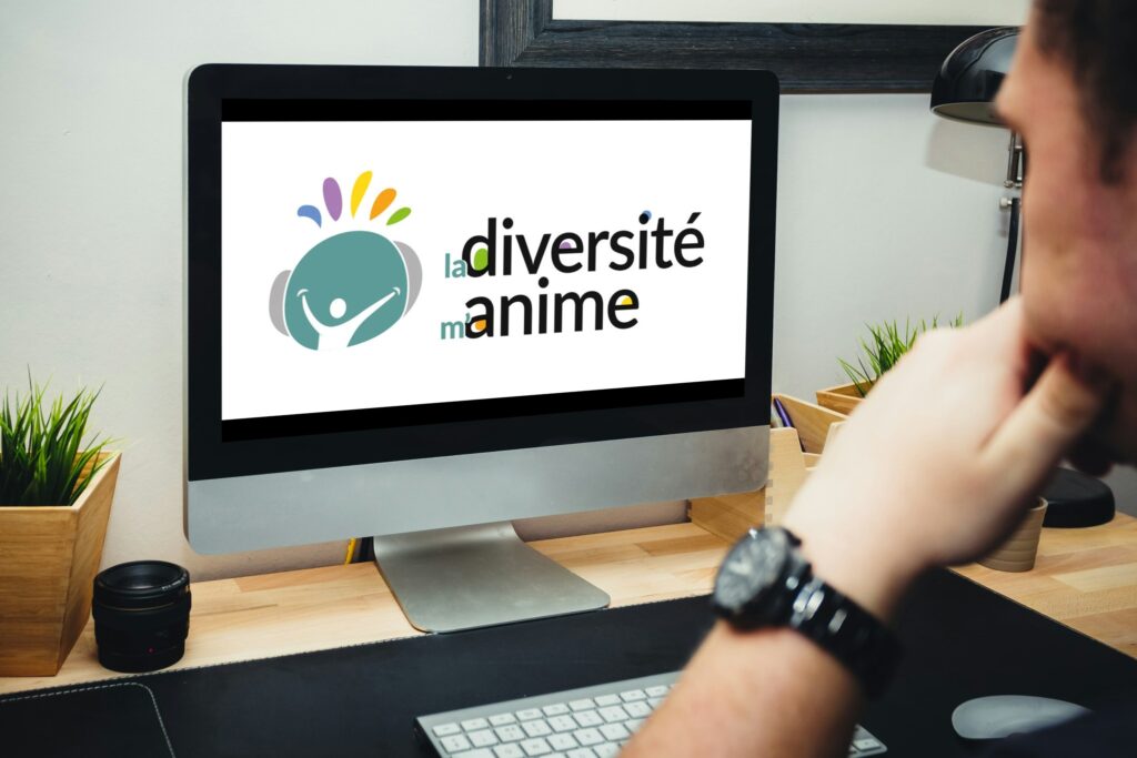 un homme devant un ordinateur. Sur l'écran est affiché un logo "la diversité m'anime"