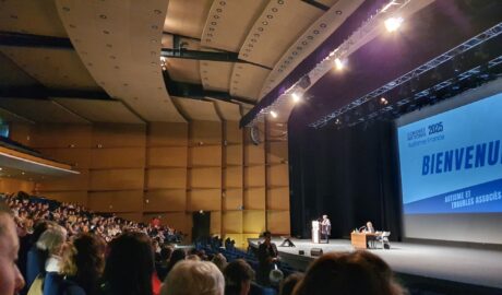 Les congressistes d'Autisme France 2025 dans la salle, l'affiche du congrès projetée sur grand écran
